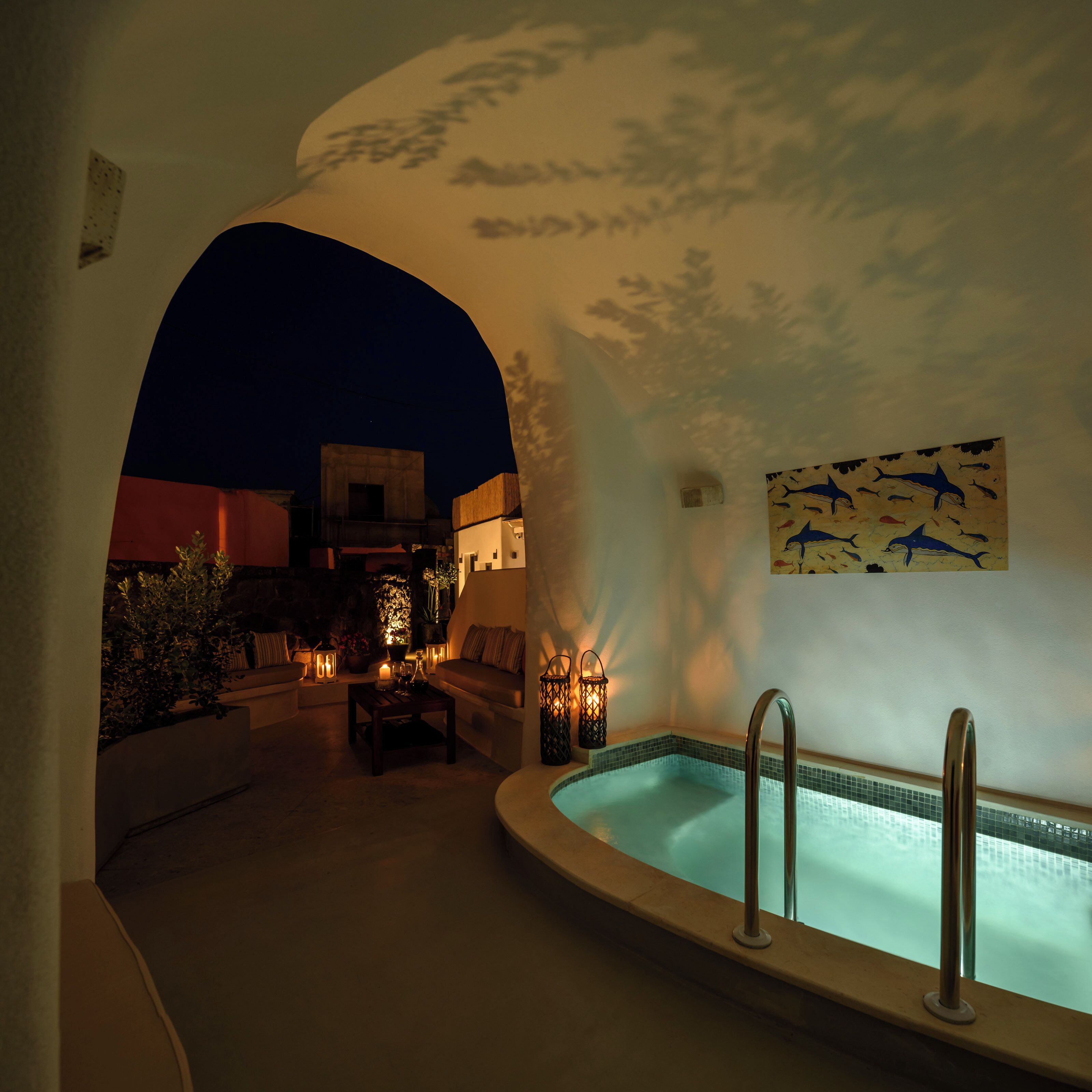 Un área de estar al aire libre con piscina, rodeada de muros con un mural decorativo.