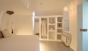 A bedroom with a large bed, a wardrobe, a mirror, and a radiator. - White Dream Suites (Santorini)