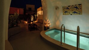 Uma área de estar acolhedora ao ar livre, com piscina, rodeada por paredes com um mural decorativo.
