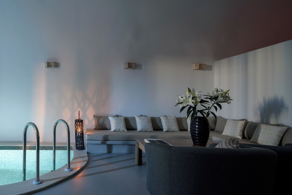 A modern living room with a pool, a sofa with patterned cushions, and a vase with flowers.