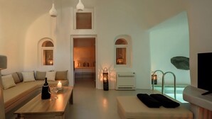 Uma sala de estar moderna com um sofá, uma mesa de centro com uma garrafa e copos, uma televisão e vista para uma piscina.