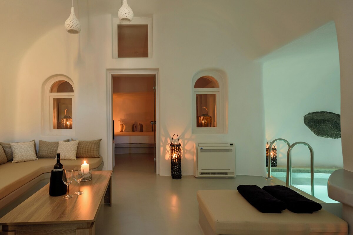 Una sala de estar moderna con un sofá, una mesa de centro con una botella y vasos, un televisor y vistas a una piscina.