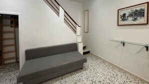 A staircase with a wooden handrail, a gray bench, and a framed artwork on the wall. - At Granny's (Carloforte)