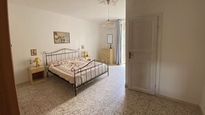 A bedroom with a bed, nightstands, a dresser, and a door. - At Granny's (Carloforte)