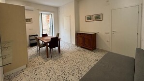 A compact room with a dining table, chairs, a cabinet, and a sofa. - At Granny's (Carloforte)