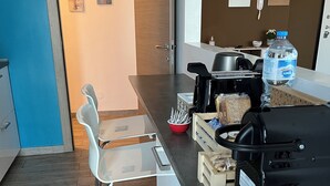 Una cocina moderna con cafetera, dispensador de agua y tostadora. Hay dos sillas y una mesa.