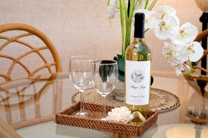 Una botella de vino sobre una bandeja con dos copas y una flor decorativa.
