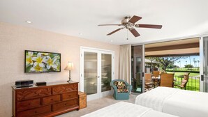 Une chambre à coucher avec un lit, une commode, un téléviseur et un ventilateur de plafond.