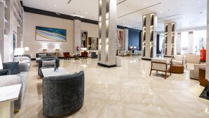 A spacious lobby with modern furniture, marble flooring, and large columns. - Novo Hotel (Riyadh)