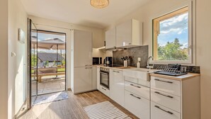 Una cocina moderna con armarios blancos, horno empotrado y un amplio ventanal con vistas al exterior.