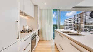 Eine moderne Küche mit Blick auf einen Hochhaus, ausgestattet mit einem großen Fenster, einem Einbauofen und einer Spüle aus Edelstahl.