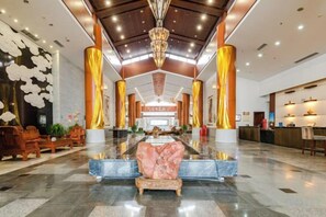 A spacious lobby with a central seating area, a reception desk, and a chandelier. - Bei Long Garden Hotel (Qingzhou)