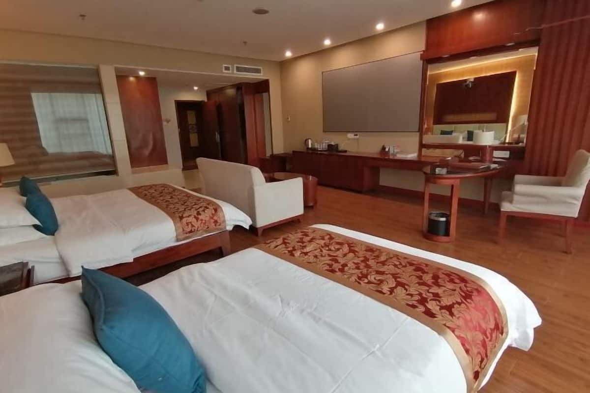Une chambre d’hôtel avec deux lits, un bureau, une chaise, un grand miroir et un téléviseur.