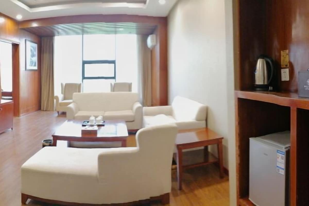 Habitación de hotel con sala de estar que incluye un sofá, una mesita de centro y un refrigerador pequeño.