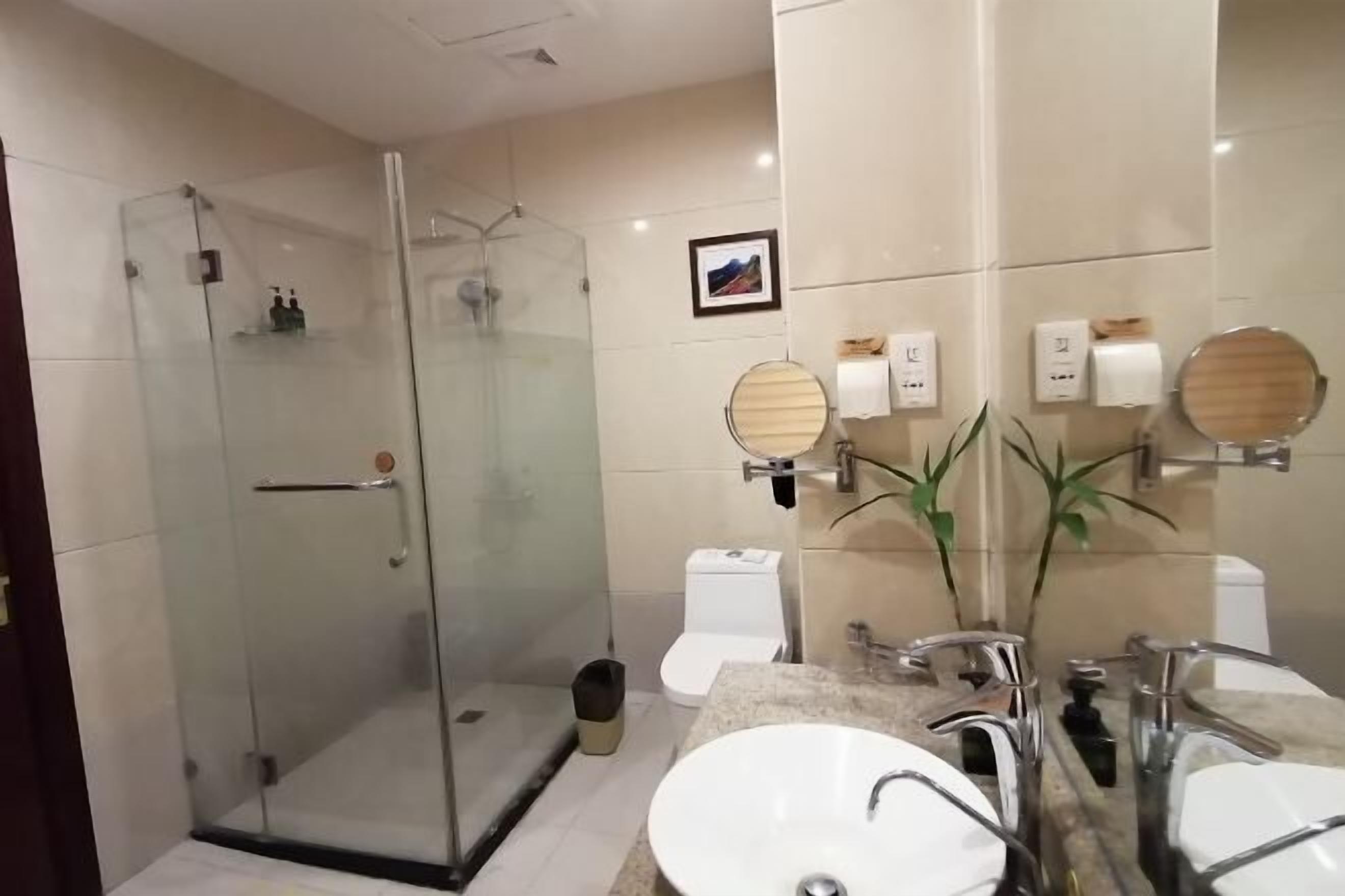 Un baño moderno con cabina de ducha de vidrio, lavabo con espejo y retrete.