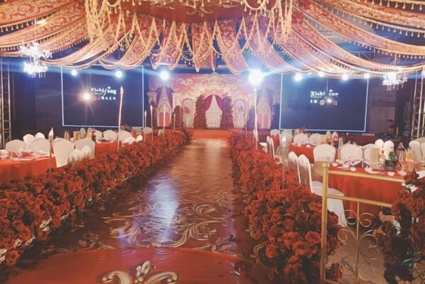 A banquet hall with a long table set for a formal event, a stage with a backdrop, and a decorative ceiling. - Bei Long Garden Hotel (Qingzhou)