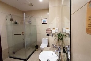 Un baño moderno con ducha de vidrio, un lavamanos blanco y un espejo.