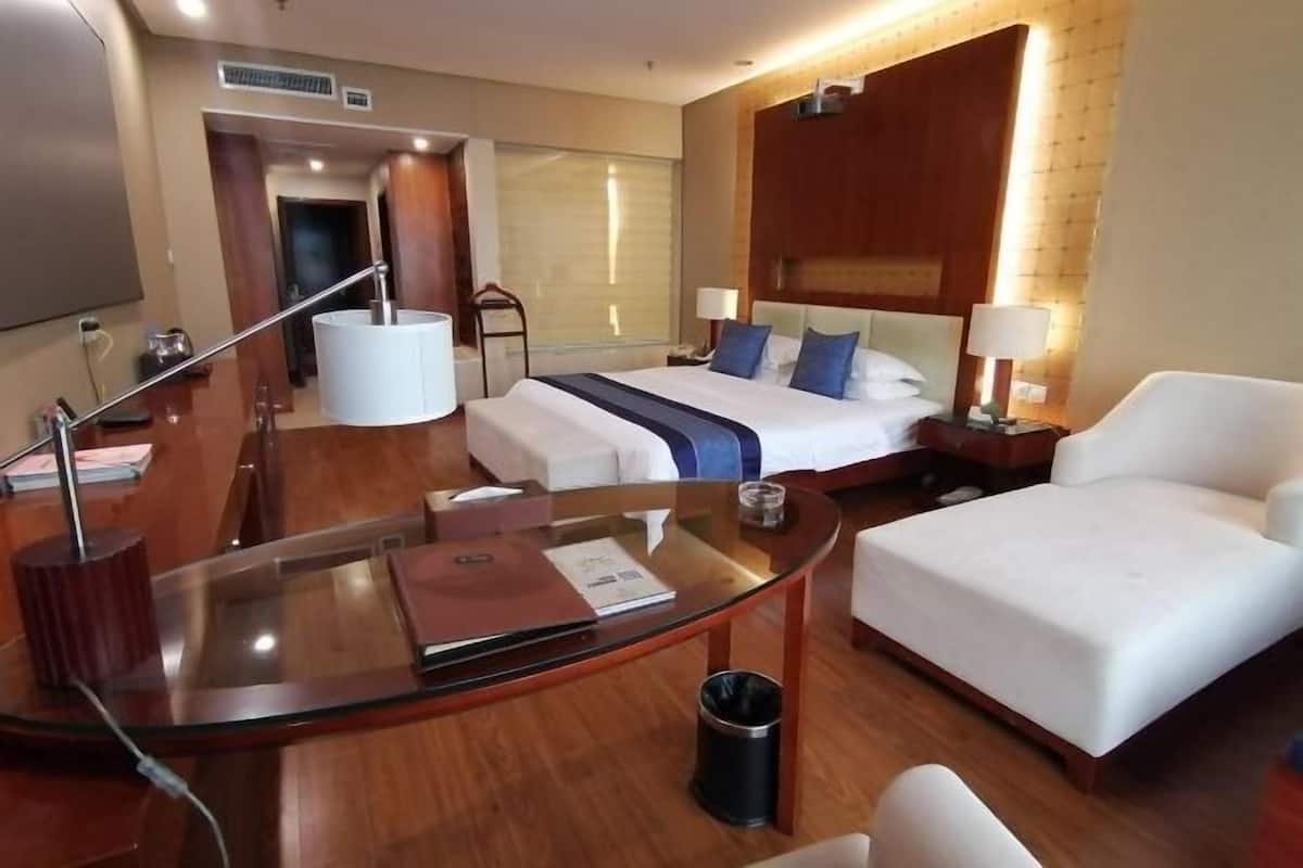 Une chambre d’hôtel équipée d’un lit, d’un bureau, d’une chaise, d’une télévision et d’une poubelle.