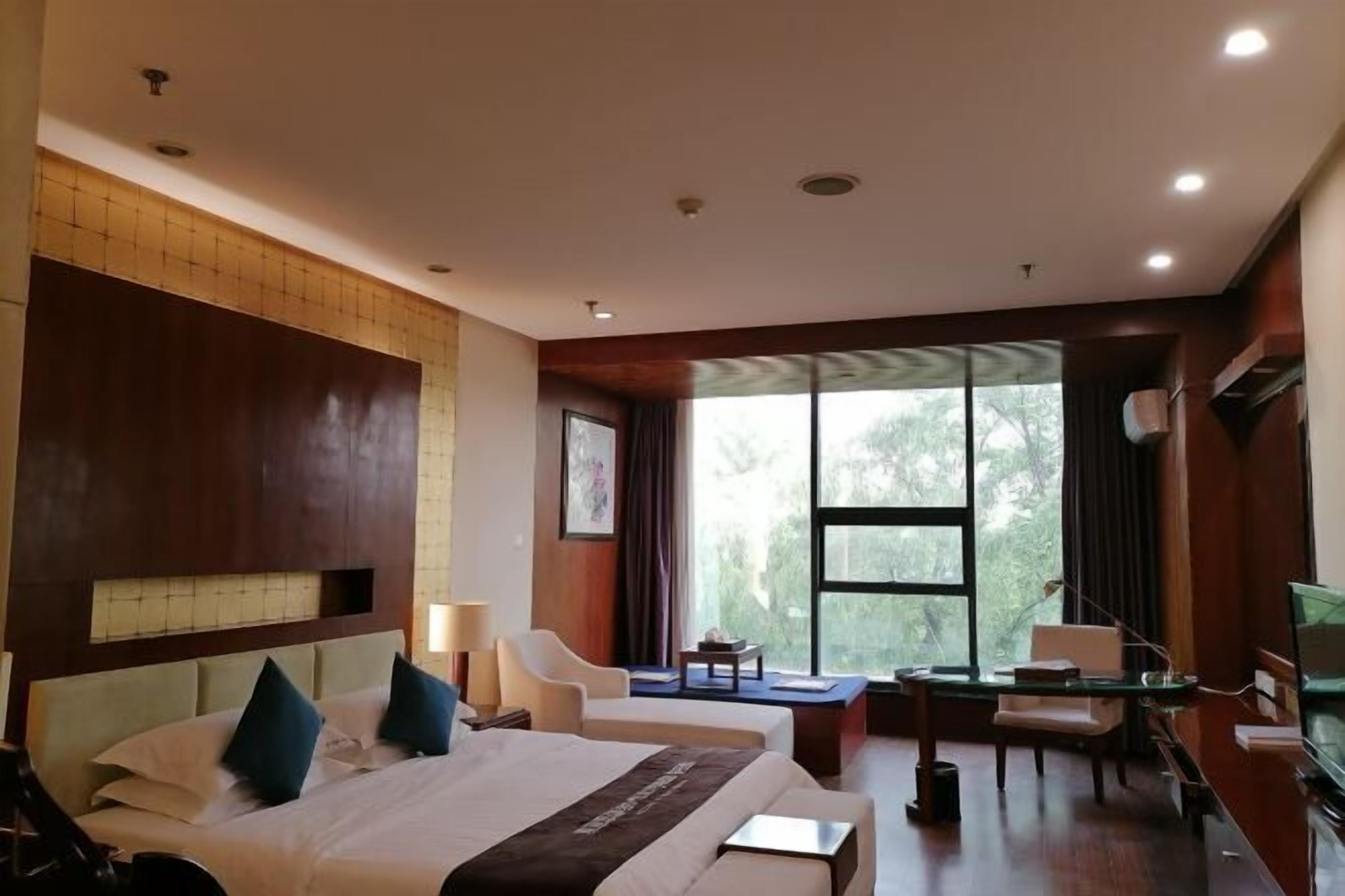 A hotel room with a large bed, a desk, a chair, and a TV.