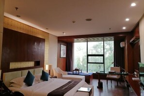 Een hotelkamer met een groot bed, een bureau, een stoel en een televisie.