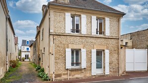 A two-story stone building with white shutters, a visible number '38', and a narrow alleyway.