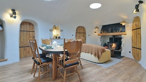 Ein gemütlicher Essbereich mit rundem Tisch, Holzsesseln und Kamin.