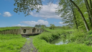 Eine Steinbrücke über einen schmalen Wasserlauf in einer üppigen grünen Landschaft.