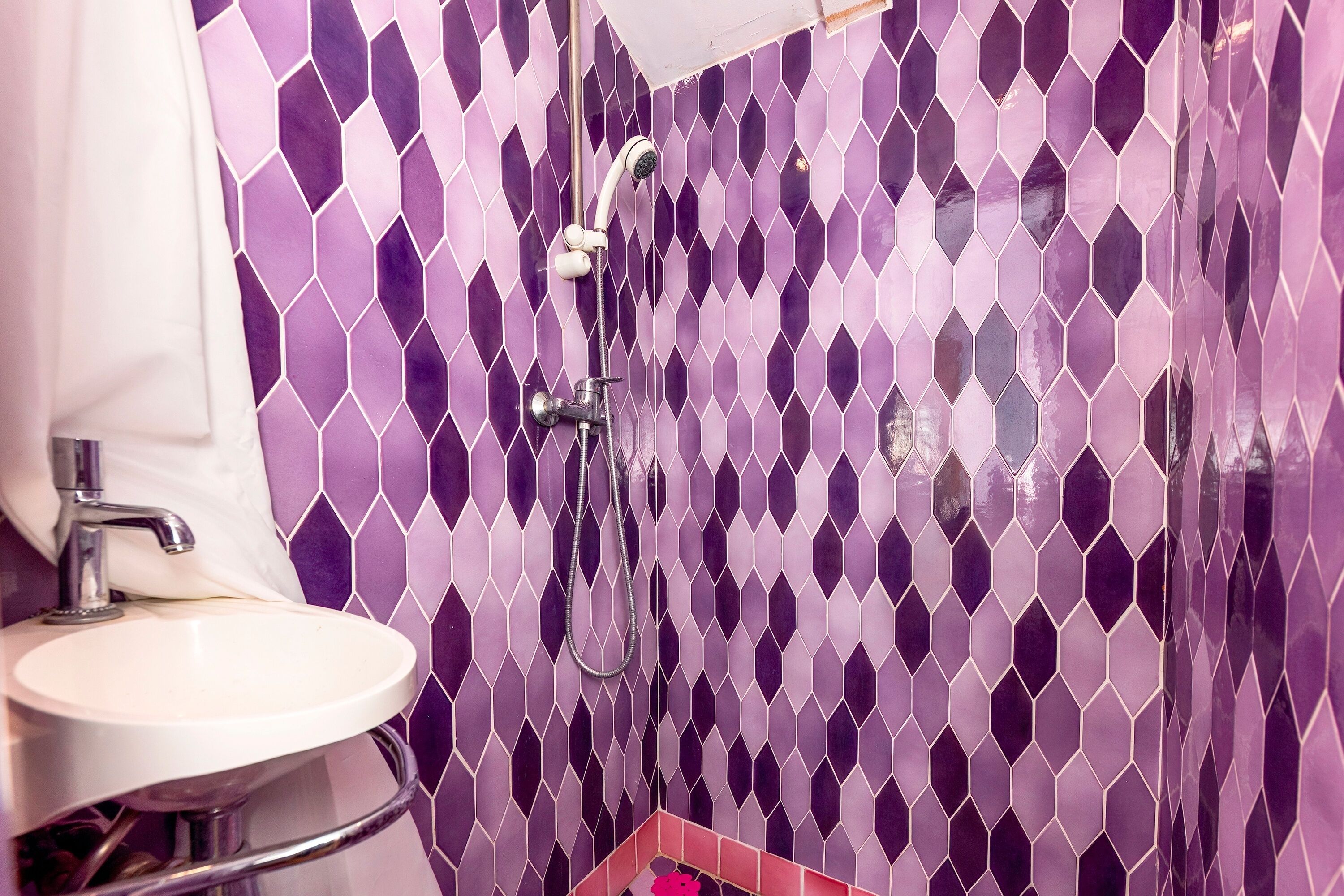 Une salle de bain avec un lavabo, une douche et un mur carrelé.