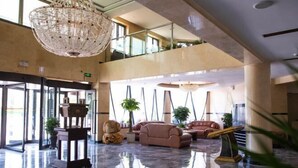 A spacious lobby with a high ceiling, a large chandelier, and multiple seating areas.