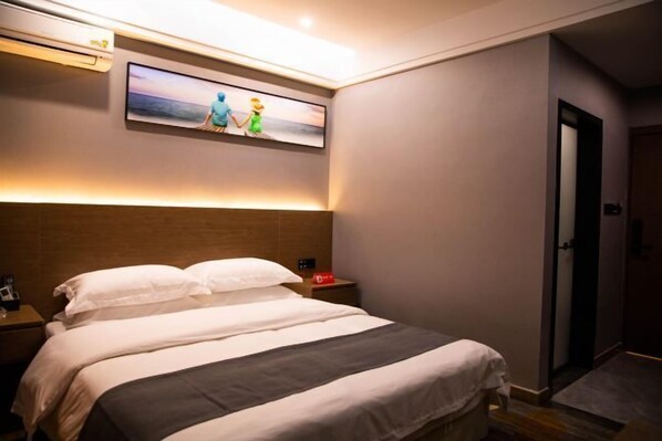 A hotel room with a large bed, a nightstand, a wall-mounted TV, and a door.