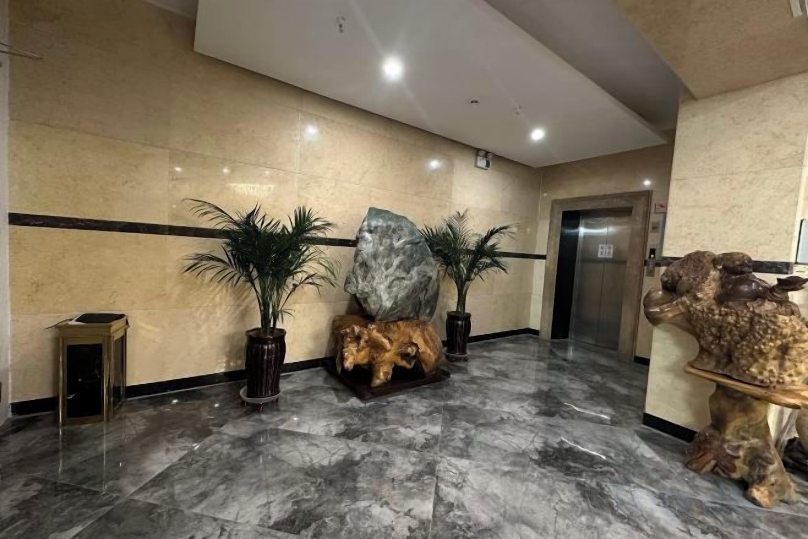 Un vestíbulo con piso de mármol, plantas en macetas y una mesa de recepción.
