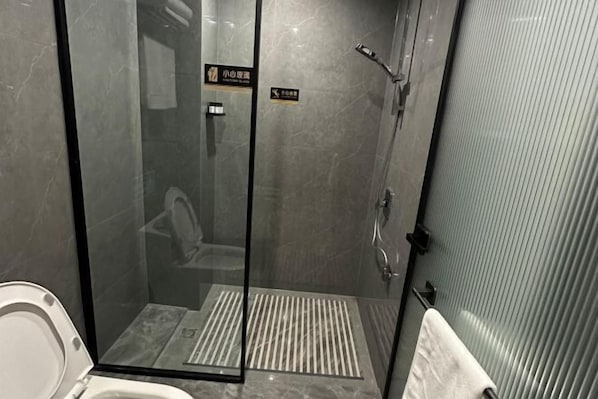 A glass-enclosed shower stall with a tiled floor, a toilet, and a towel rack. - Shenhe Hotel (Habahe)