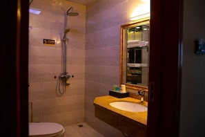 A small, private bathroom with a toilet, a sink, and a shower. - Shenhe Hotel (Habahe)