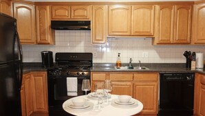 Una cocina con armarios de madera, estufa negra, fregadero y lavavajillas.