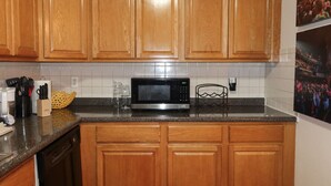 Una cocina con armarios de madera, microondas y una estantería para vinos.