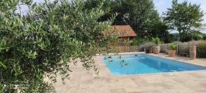 Ein Schwimmbecken, umgeben von einem Holzzaun, mit einem Haus im Hintergrund.