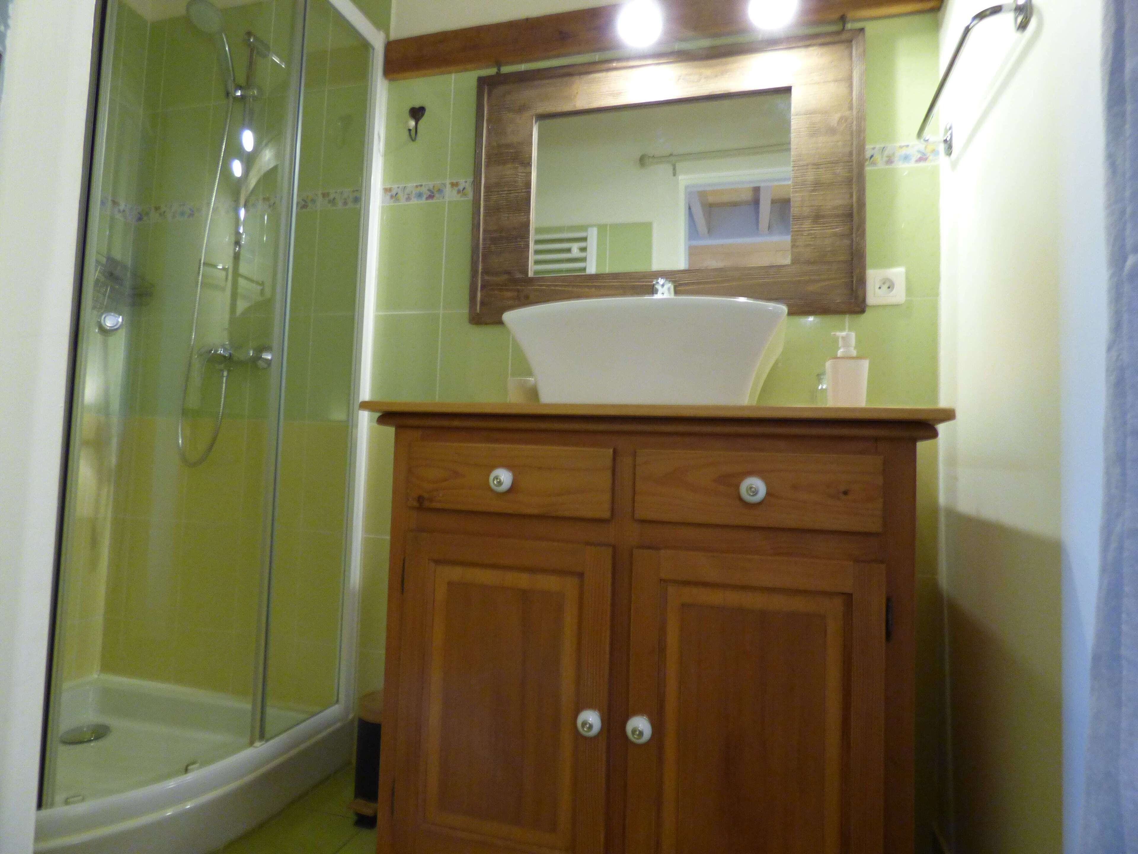 A bathroom with a shower, a sink, and wooden cabinets.