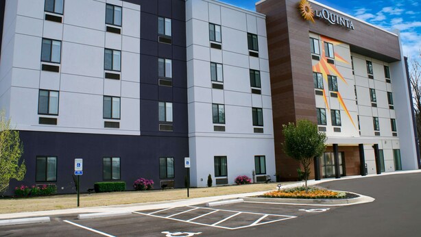 A modern hotel with a flat facade, multiple windows, and a prominent logo on the side.