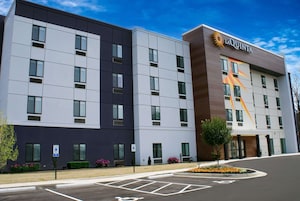Un hotel moderno con fachada plana, múltiples ventanas y un logotipo destacado en el lateral.