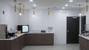 A modern kitchen with a flat-screen TV, a coffee machine, and a toaster on the counter.