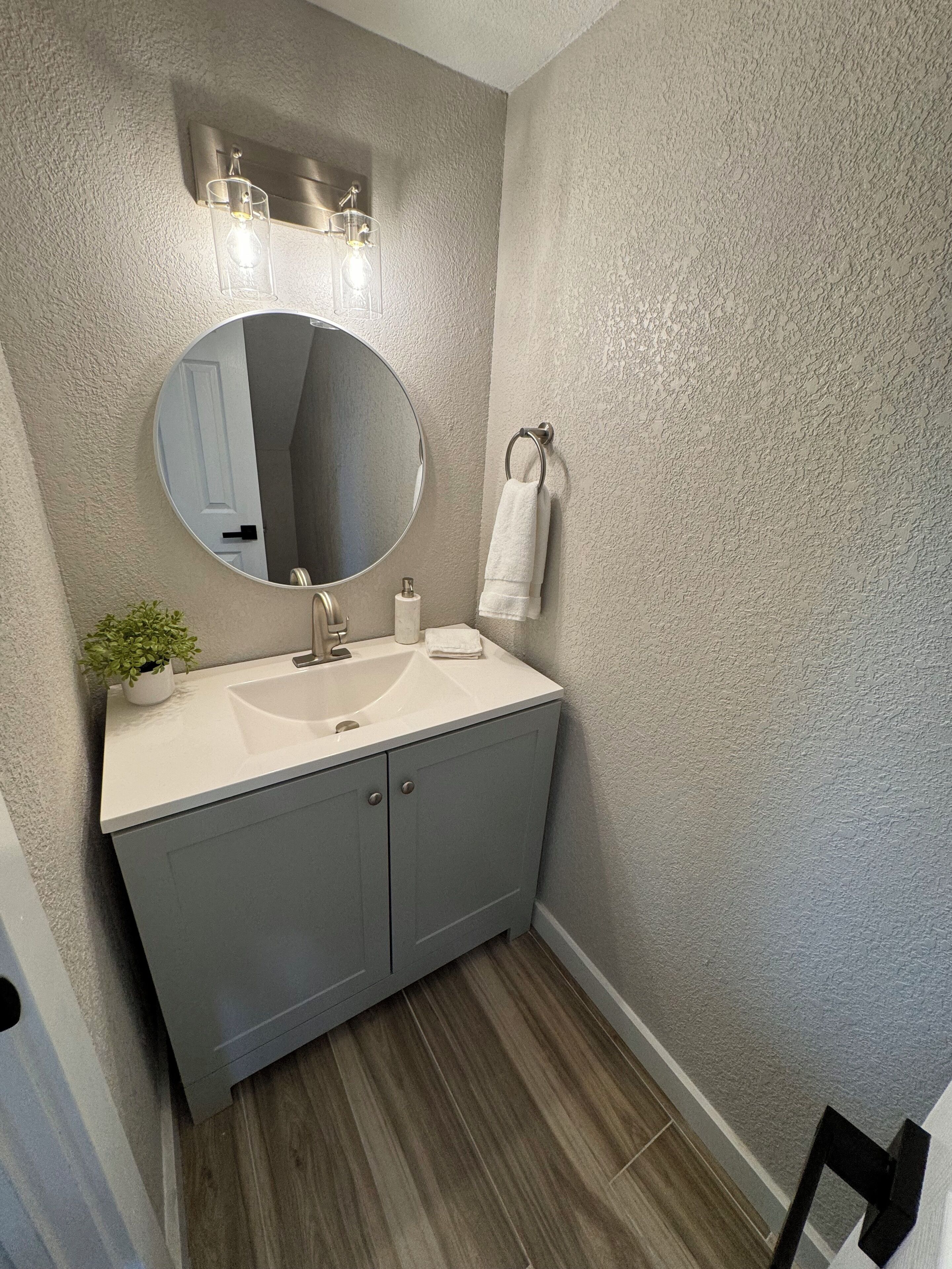 Une salle de bain avec un miroir rond, un lavabo et un porte-serviettes.