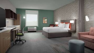 A hotel room with a bed, a desk, a chair, a small ottoman, and a window.