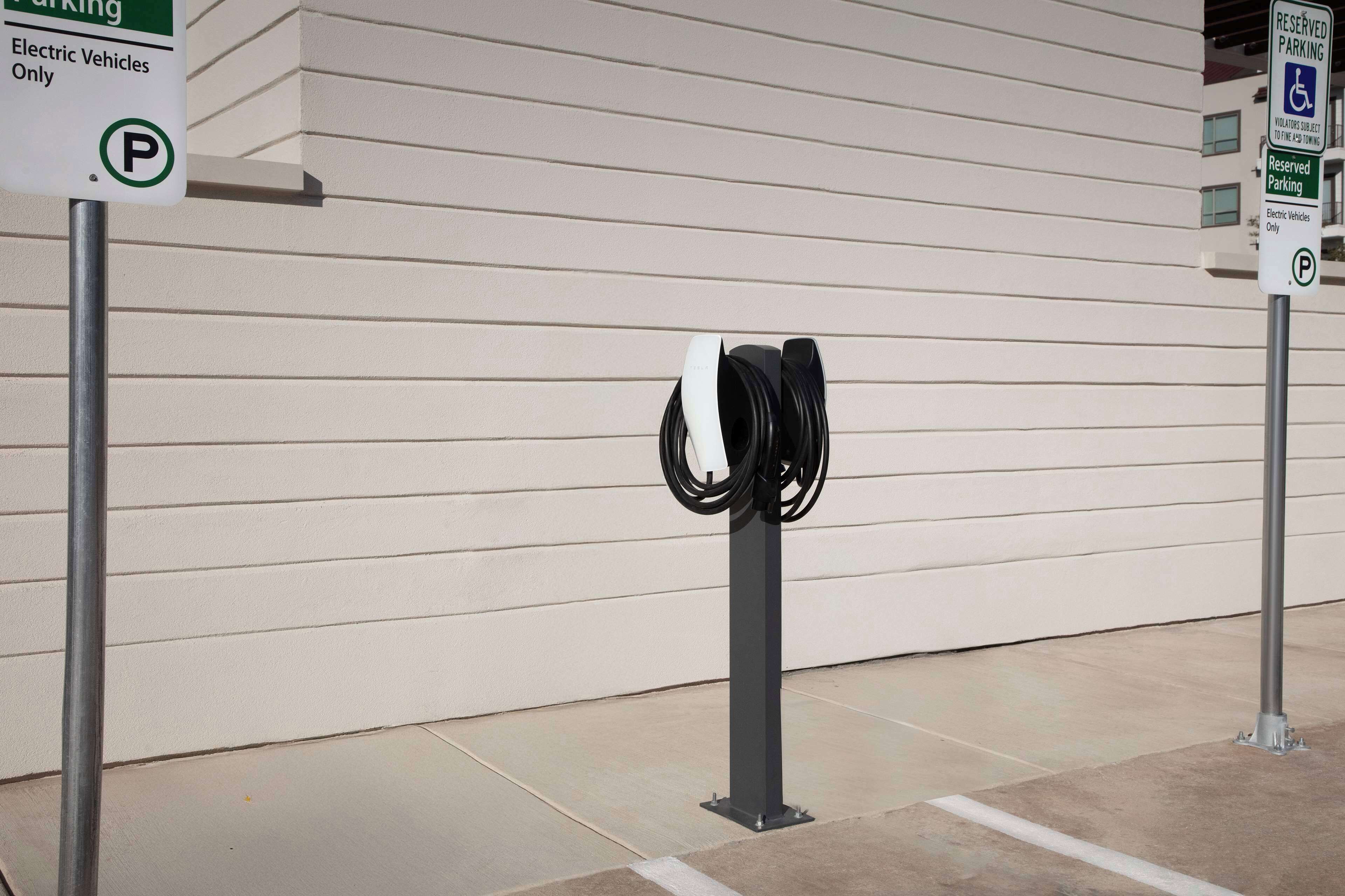 Ein Parkbereich mit Ladestationen für Elektrofahrzeuge und Hinweisschildern für ausgewiesene Stellplätze für Elektroautos.