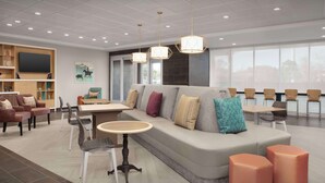 A modern hotel lobby with a large sofa, dining area, and seating. - Home2 Suites By Hilton Georgetown Austin North (Georgetown)