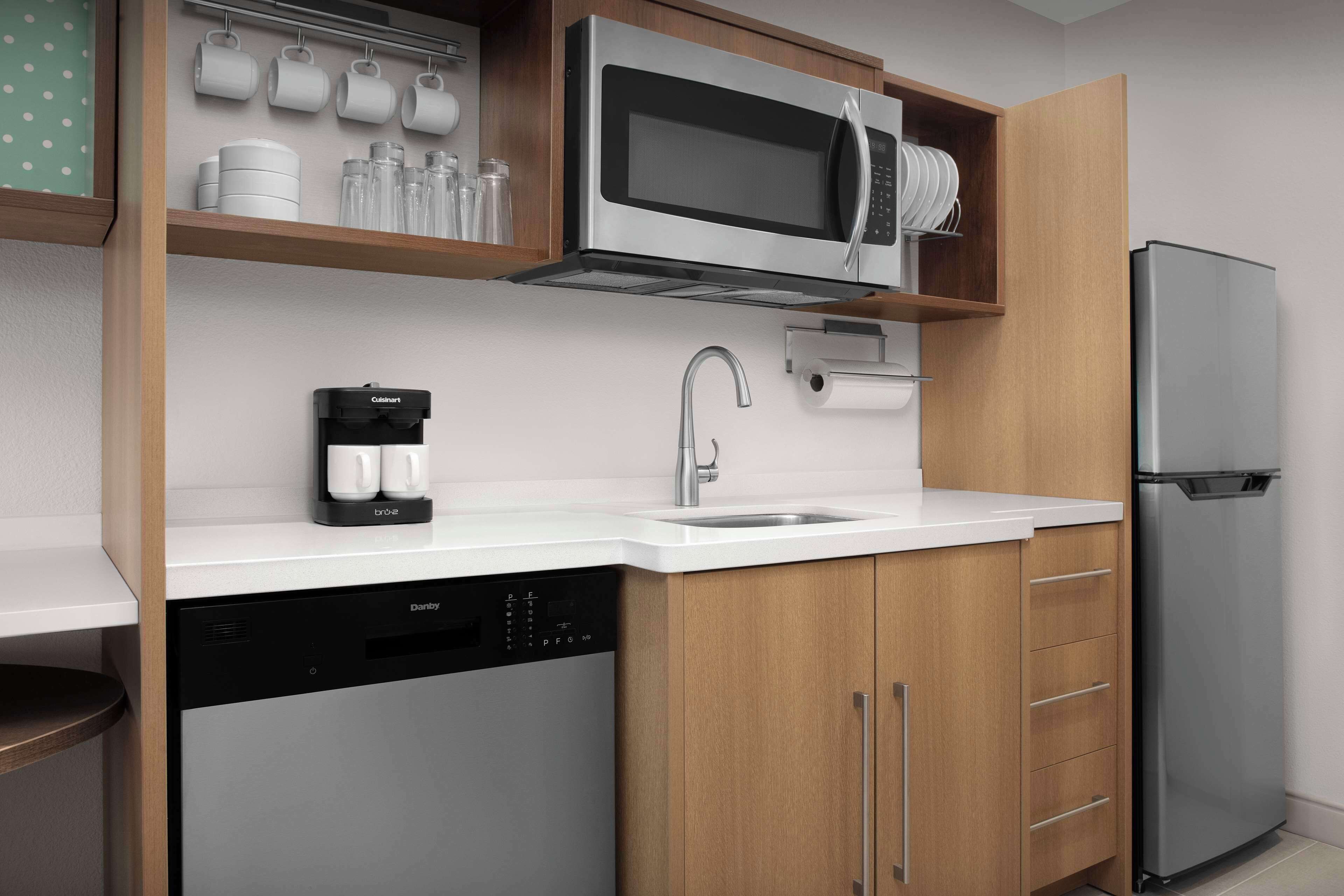 Uma cozinha moderna equipada com lava-louças embutida, máquina de café, micro-ondas e frigorífico.