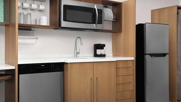 A modern kitchen with a dishwasher, a microwave, a coffee maker, and a refrigerator.