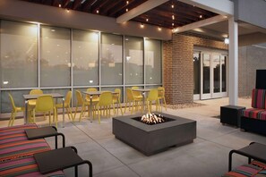 An outdoor seating area with yellow chairs, a fire pit, and a covered patio. - Home2 Suites By Hilton Georgetown Austin North (Georgetown)