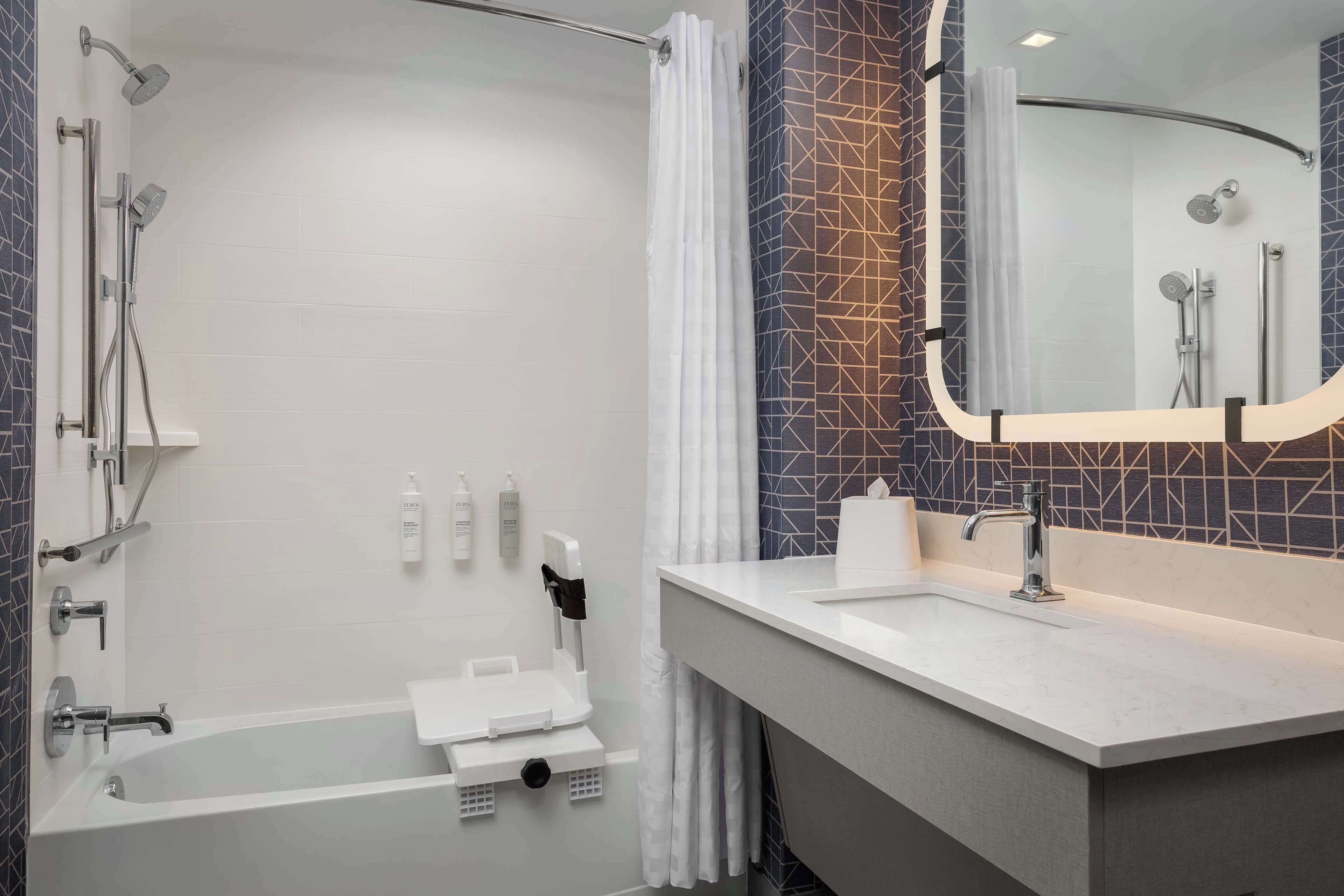A modern bathroom with a bathtub, shower, and vanity with a mirror.