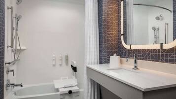A modern bathroom with a bathtub, shower, and vanity with a mirror.