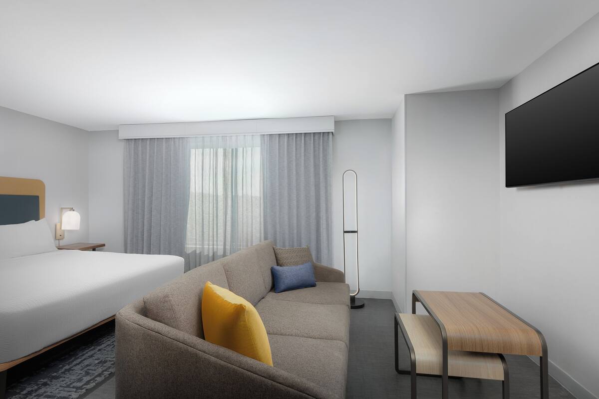 Una habitación de hotel moderna con cama, sofá y escritorio.